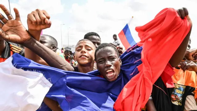 Manifestation pro-russe au Niger en 2023 : un homme agite un drapeau russe tandis que des partisans des chefs militaires se rassemblent